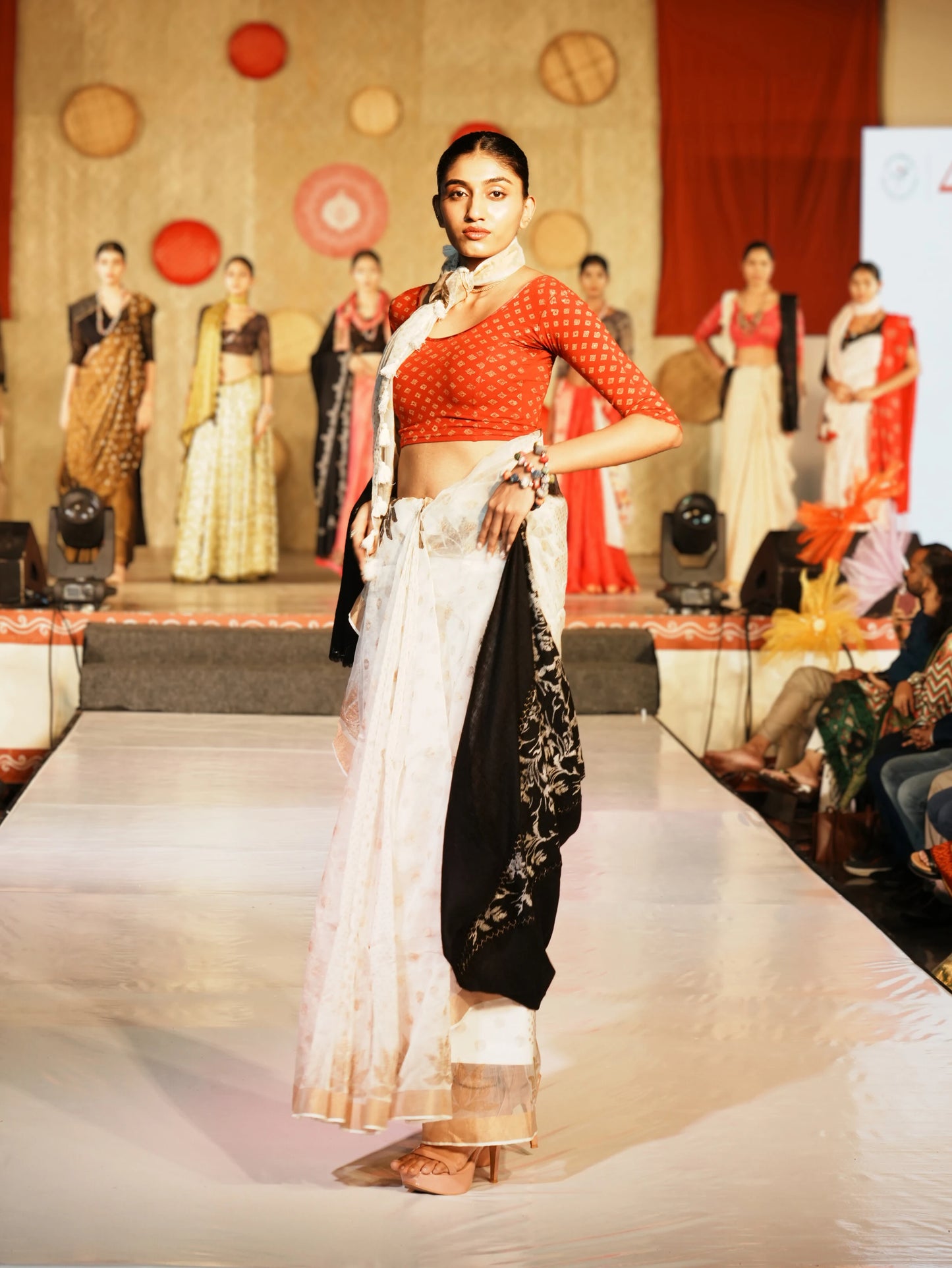 Model walking on a fashion show runway wearing a red top and white saree. Bani Thani Kamalika Saree by Soulweaves