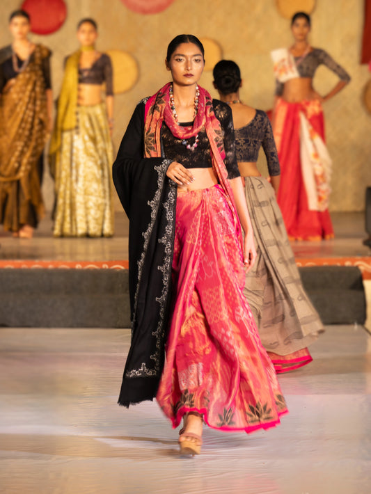 Model walking on a catwalk wearing a traditional outfit with a pink and black design. Bani Thani Padmapriya Saree by Soulweaves