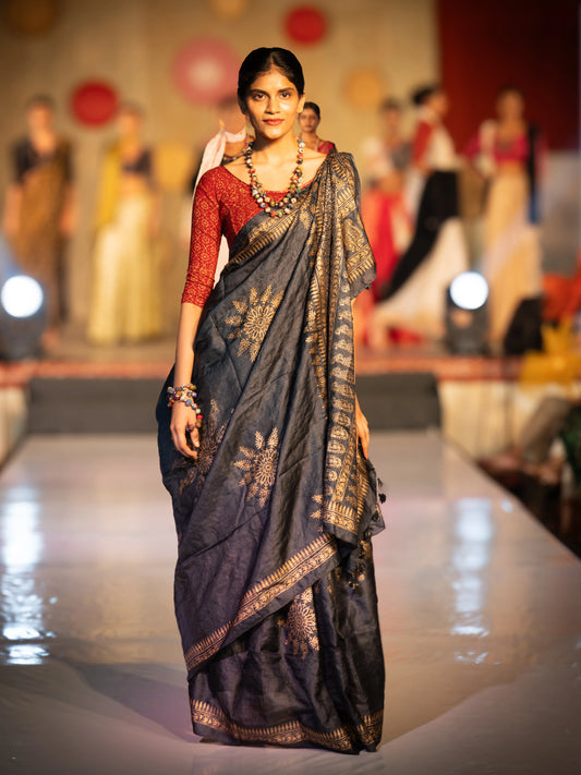 Woman in a saree walking on a fashion show runway with other models in the background. Bani Thani Rajsi Saree by Soulweaves