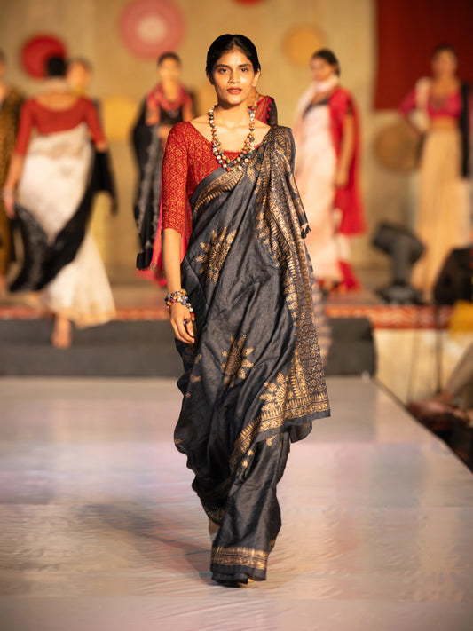 Woman in a saree walking on a fashion show runway with other models in the background. Bani Thani Rajsi Saree by Soulweaves
