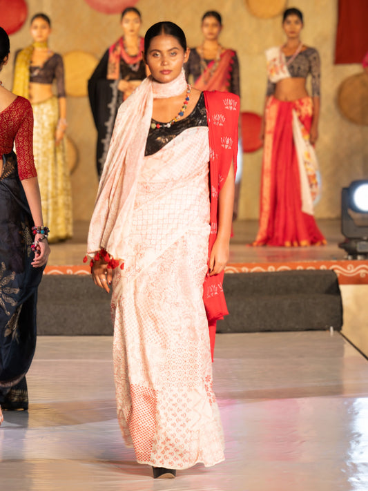 Model wearing a white saree with red border on a fashion show stage. Bani Thani Rudraja Saree by Soulweaves