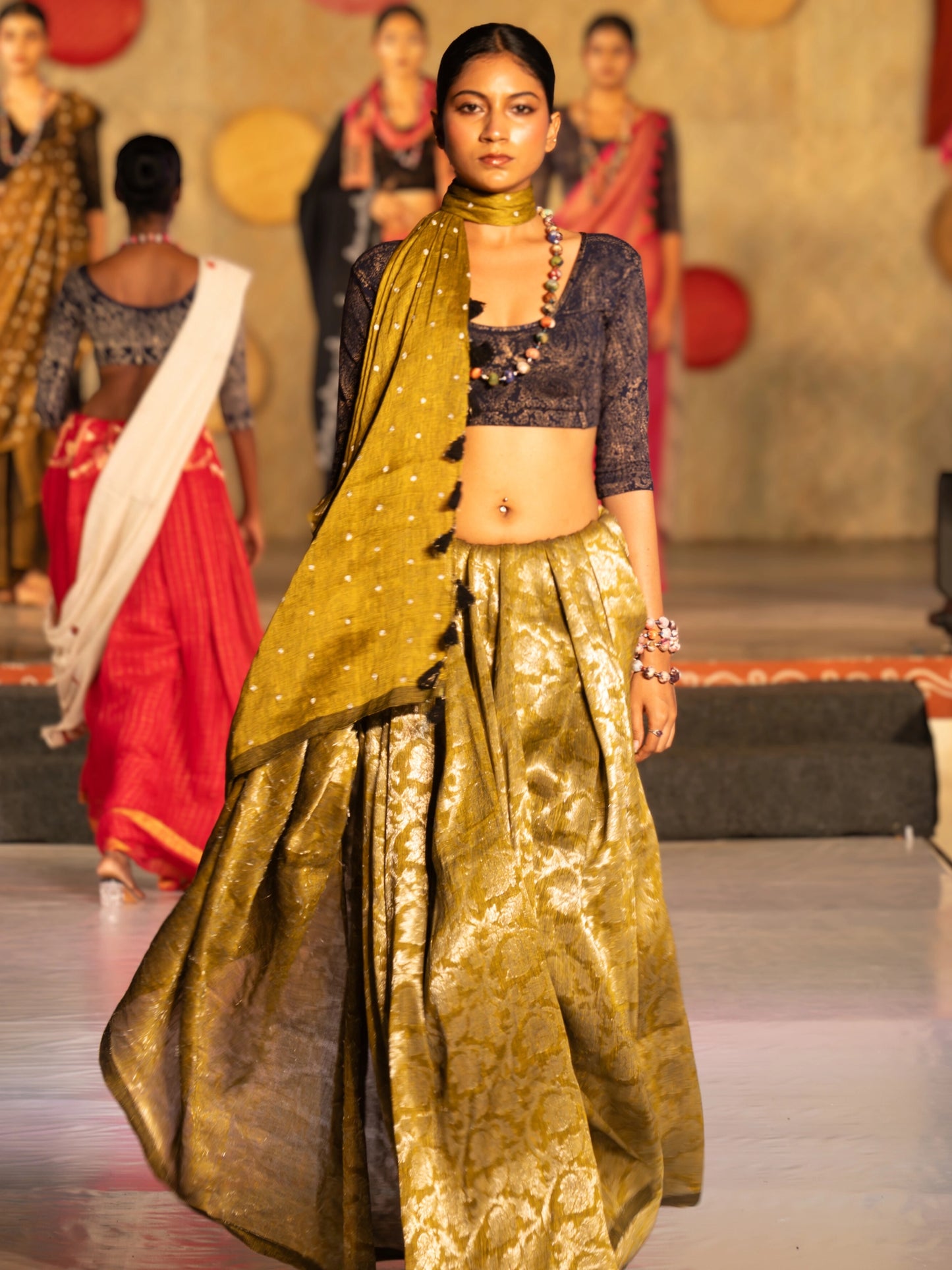 Soulweaves's Pallavi Saree collection - Woman in a traditional outfit on a fashion show runway with other models in the background.