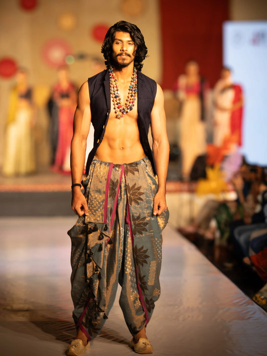 Man walking on a fashion show runway wearing a traditional outfit with a patterned dhoti and vest. Rudrangi Dhoti Saree by Soulweaves