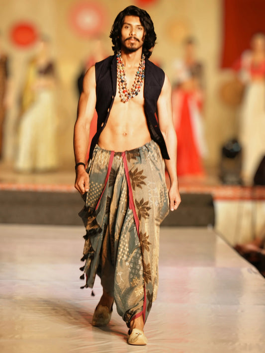 Man walking on a fashion show runway wearing a traditional outfit with a patterned dhoti and vest. Rudrangi Dhoti Saree by Soulweaves